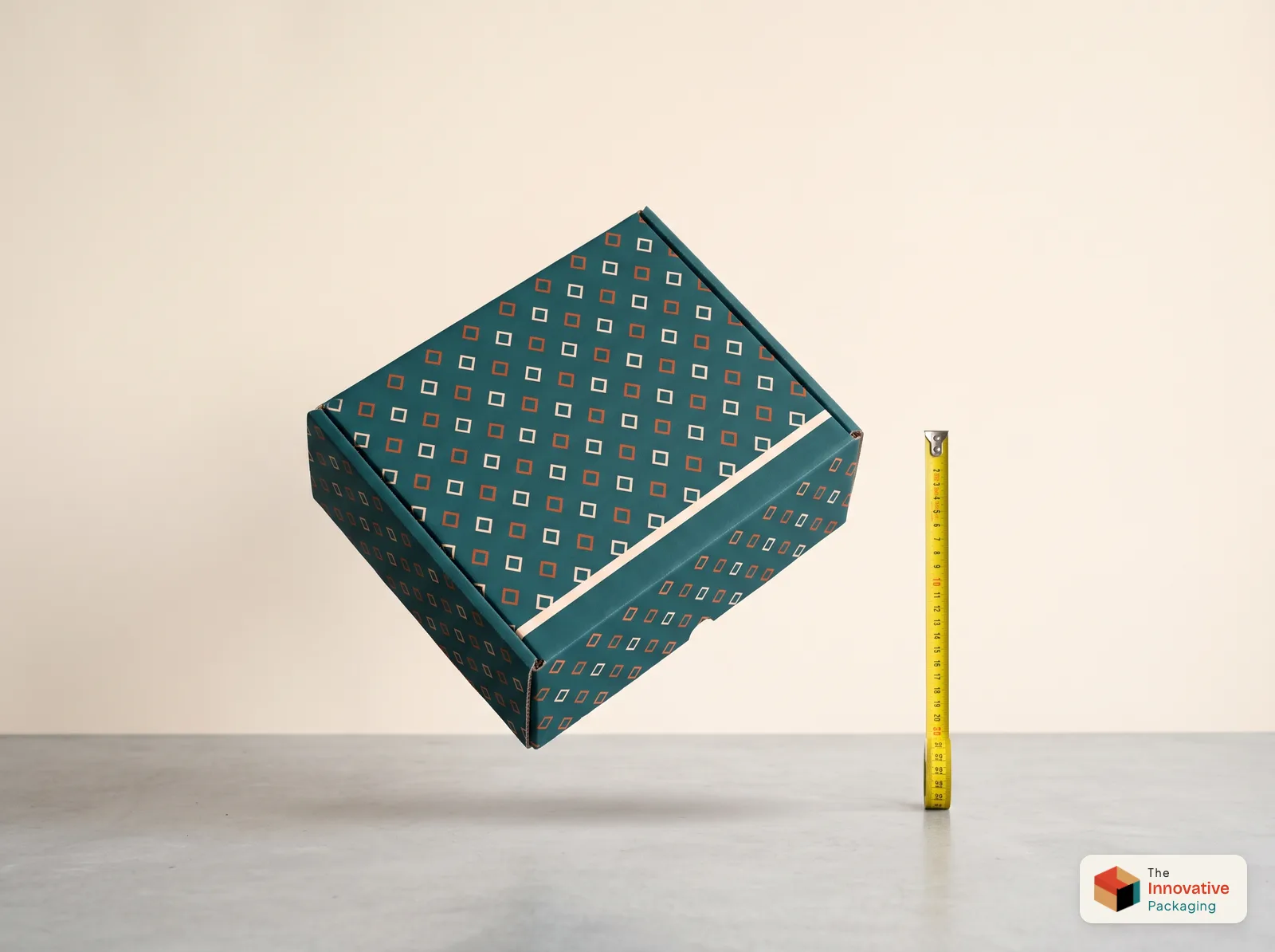 A teal printed mailer box with an orange and cream pattern falling corner-first above a concrete floor, next to an extended tape measure